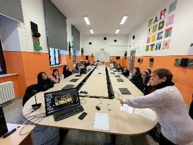 SchĂŒler*innen sitzen mit einer Lehrkraft an einem groĂen Tisch