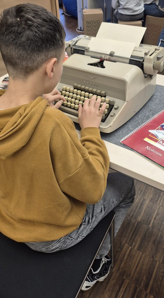 ein Schüler tippt auf einer Schreibmaschine